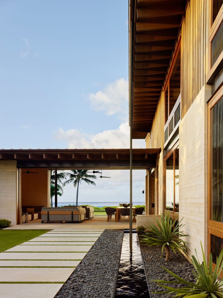 Residence with deep overhangs, a stone path and a water rill leading toward the ocean.